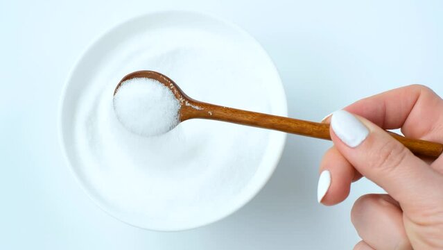 Erythrol sweetener in glass bowl on white background, top view.