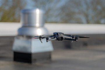 Drone being used to perform an aerial inspecting of HVAC RTU equipment on a commercial roof.