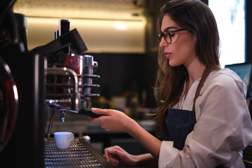 Fototapeta na wymiar Barista standing in a coffee shop and making espresso on a coffee machine.