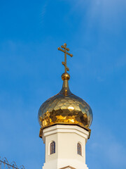 Fototapeta na wymiar Gilded dome with a cross of an Orthodox church against a blue clear sky