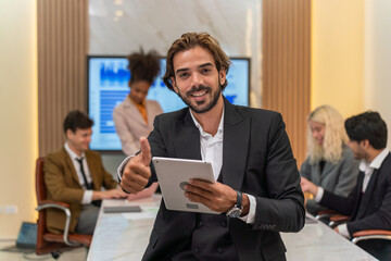 Handsome businessman looking at the sales report using his digital tablet and smile happily celebrate the latest successful in closing and inked a big deal