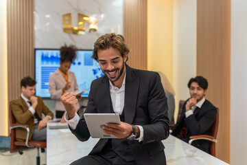 Handsome businessman looking at the sales report using his digital tablet and smile happily celebrate the latest successful in closing and inked a big deal