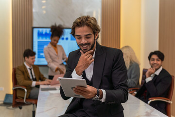 Handsome businessman looking at the sales report using his digital tablet and smile happily celebrate the latest successful in closing and inked a big deal