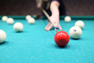 Female player ready to hit red ball on blue pool table