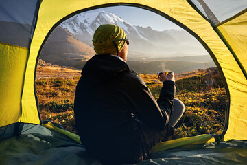 Man relaxing in his tent in the mountains