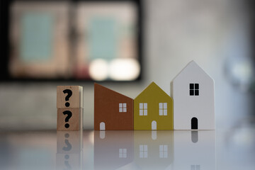 Miniature house model with question mark, looking for new home, buy or rent real estate concept