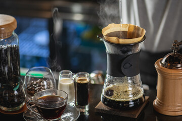 drip coffee, Barista making drip coffee by pouring spills hot water on coffee ground with prepare filter from copper pot to glass transparent chrome drip maker on wooden table in cafe shop