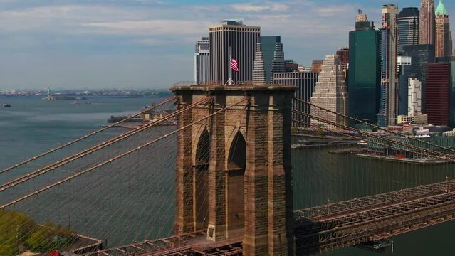 American Flag flying in the wind on Brooklyn Bridge with NYC Manhattan buildings in background on beautiful summer day aerial