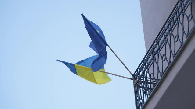 Handheld shot of the Ukraine and Europe flag waving in the wind, concept help