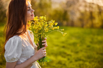 portrait of a woman with a bouquet of wild flowers in the rays of the setting sun in a field