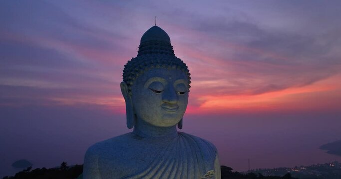 aerial view amazing colorful pink light in purple sky at twilight behind Phuket big Buddha head..Phuket Big Buddha is important and famous landmarks in Phuket.4k Video for travel and religious ideas.