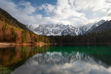 A beautiful green lake with reflections of snow-capped mountains.