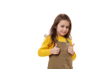 Isolated portrait on white background of an amazed happy excited Caucasian little child girl, showing thumbs up gesture, approval sign, expressing happiness and agreement. Excellent feedback.