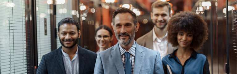 Group of happy, motivated business people standing together at office with their leader