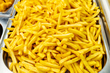 French fries on a large metal tray. Cooking fast food in a cafe or canteen. Close up