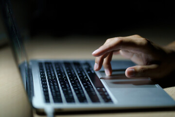 Close up of a man's hands on keyboard of lap top in the dark room, people working at home, modern white notebook. Internet, work, technology concept.
