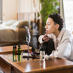 鏡を見ながらメイクをしている若い日本人男性/メンズビューティー