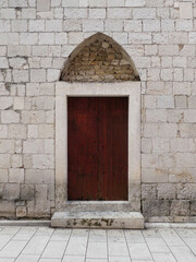 old wooden door in wall of the first University in Zadar, Croatia