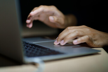 Close up of a man's hands on keyboard of lap top in the dark room, people working at home, modern white notebook. Internet, work, technology concept.