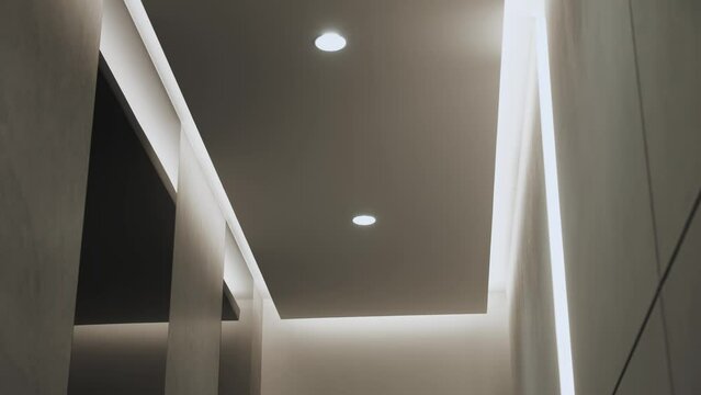 Round modern ceiling lamp in minimalist interior with hidden LED backlight. Minimalist Interior with lighting equipment. Contemporary modern lamp. Luxury Chandelier, slow motion dolly shot.
