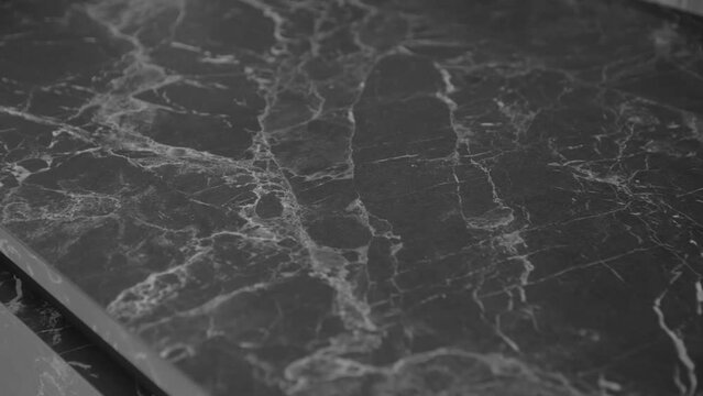 Close-up shot of beautiful granite black and grey counter top, camera moving slow motion. Kitchen design with counter top made of granite stone. Texture and background.