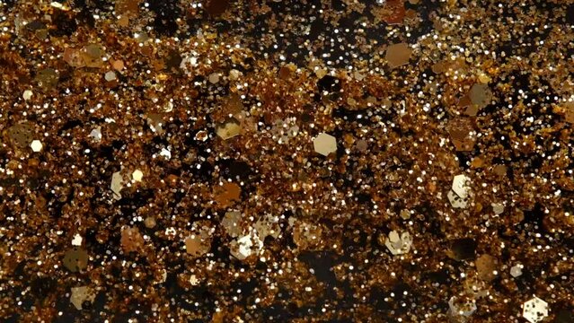 slow motion of abstract gold sparkle on black background. Beautiful transition with real gold particles. flying in wind on black background, shot with depth of field.