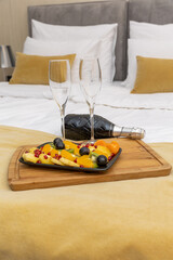 Fruit salad,champagne and glasses on a hotel bed