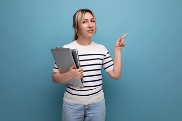Naklejka premium close-up of a successful blonde woman freelancer in a striped sweater holding a laptop in her hands on a blue background