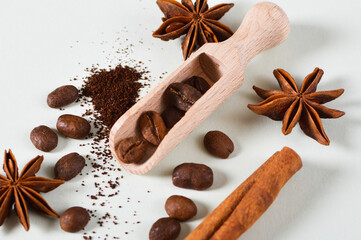 Close-up roasted coffee beans in scoop with spices, cinnamon stick, star anise