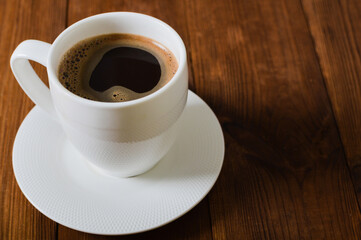 Coffee break - white cup of coffee on the wooden background