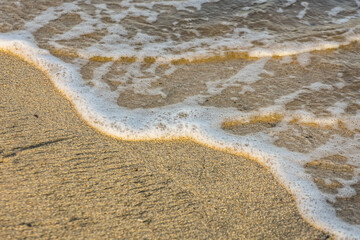 wave with white foam at the sandy beach in egypt detail view