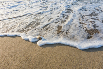 waves with white foam at the fine sand from the beach during sunrise in egypt macro
