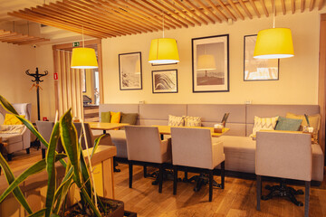 Stylish cafe interior. Sofa and comfortable chairs in restaurant. Indoor cafe furniture. Empty lounge zone with warm light lamps. Hotel lobby design. Modern home design. Dinner room decoration. 
