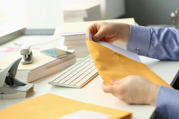 Man holds apaper envelope with business mail at workplace. Receiving correspondence and bank...