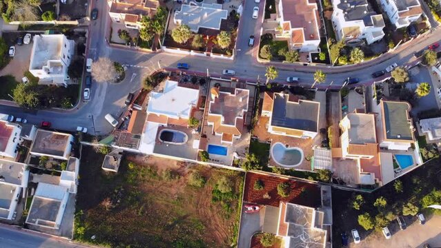 Drone footage facing down on houses with pools on Ibiza.