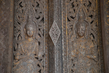 Fototapeta na wymiar Patterns of angels carved from wooden on the church door of Wat Pa Ruak, which is an abandoned temple. Located at the way up Mount Phousi. At Central Luang Prabang city in Northern of Laos.