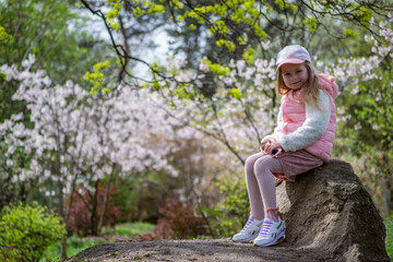 Naklejka na ściany i meble cute little girl in a pink dress walks in the spring park