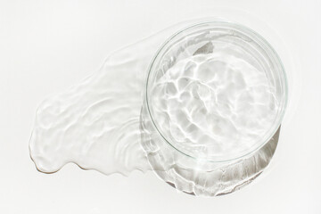 An empty Petri dish is poured out with spilled water or liquid. Waves, lab, reaction.