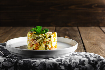 Traditional russian salad Olivier from boiled vegetables and sausage with mayonnaise in bowl. Russian New Year or Christmas salad on wooden background with copy space.