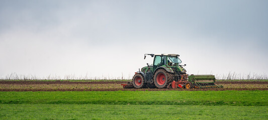 Agriculture country background panorama landscape - Tractor on field on horizon with blue sky