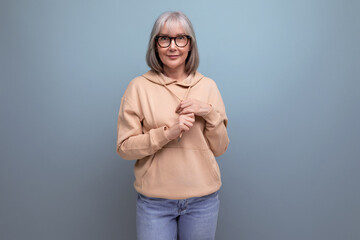 portrait of a dreamy middle-aged woman with gray hair in a casual look on a studio background with...