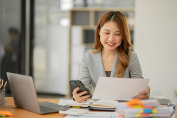 Asian businesswoman reading graphs and talking on phone with customers in office