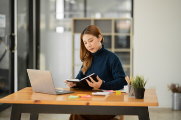 Fototapeta premium Asian businesswoman holding notebook about business, spending money.