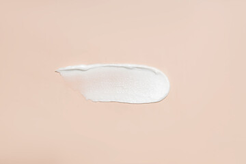 Cosmetic product smear white moisturizing lotion cream on beige, squeezed out and smeared portion of skincare cream product testing. - obrazy, fototapety, plakaty