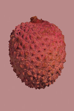 Close up textured detail of red lychee fruit on pink background
