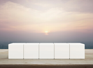 Five white block cubes on wooden table over modern city tower and skyscraper at sunset, vintage style