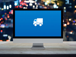 Delivery truck flat icon on desktop modern computer monitor screen on wooden table over blur colorful night light traffic jam road in city, Business transportation online service concept
