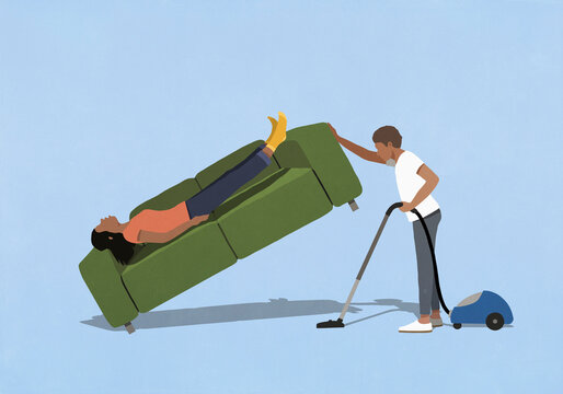 Husband vacuuming under wife sleeping on sofa at home
