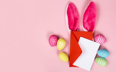 congratulatory post card with easter eggs and with blank white note on the pink background and rabbit ears and place for text top view