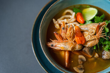 A bowl of food with shrimps and vegetables on a table.